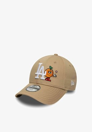 Beige baseballpet met wit "LA"-logo en geborduurd oranje cartoonfiguurtje dat aan de voorkant een klein rond voorwerp vasthoudt.