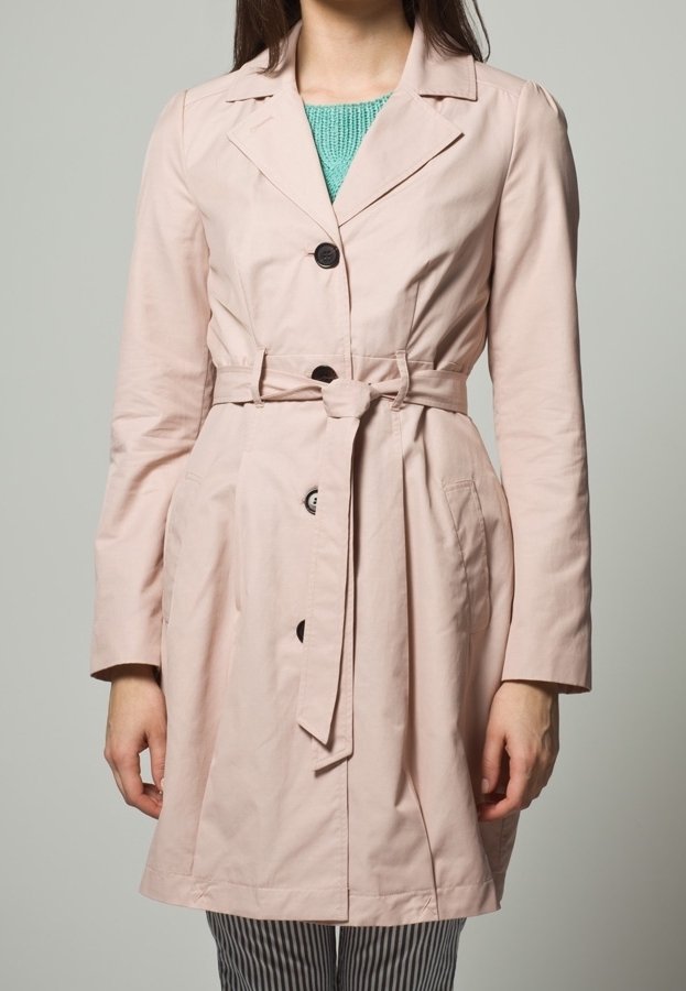 Ljust rosa trenchcoat med knytning i midjan, dubbelknäppta knappar och slagkrage. Tillverkad av mjuk, lättviktig tyg.