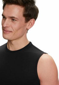 Top nero senza maniche realizzato in tessuto morbido, con scollatura rotonda e design minimalista, caratterizzato da cuciture sulle spalle sottili.