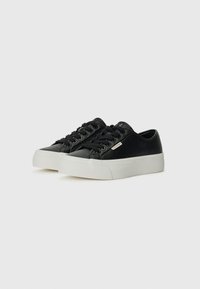 Black leather sneakers with a white rubber sole. Features round toe, lace-up closure, and a logo plate on the side. Clean design.