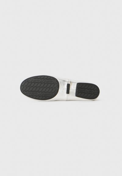 Semelle de chaussure en cuir argenté avec un motif de semelle en caoutchouc noir, montrant les sections de grip avant et talon sur un fond blanc.