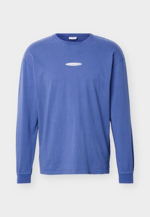 Sinine pikkade varrukatega ümmarguse kaelusega särk, millel on valgel ovaalsel logol rinnal keskel tekst, esitletud tavalise taustaga.