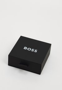 Must kast, mille siledus ja väljatõmmatava sahtliga, mille peal on sõna "BOSS" julgete valgete tähtedega.
