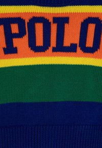 Sweter z dzianiny z wyrazistym napisem "POLO" w ciemnoniebieskim kolorze. Strzały w pomarańczowym, żółtym, zielonym i granatowym tworzą żywy wzór kolorystyczny.