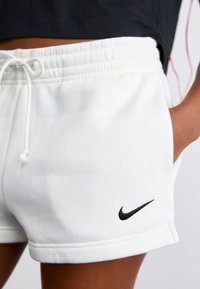 Fehér pamut rövidnadrág elasztikus derékkal, húzózsinórral és egy kis fekete Nike logóval a bal alsó oldalon.