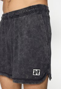 Svarte bomuldsshorts med en falmet tekstur, elastisk talje og et lille kontrastfarvet Nike-logo i hjørnet af kanten.