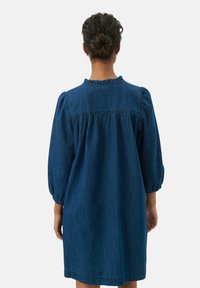 Denim ruha összegyűrt dekoltárral, háromnegyedes puffos ujjakkal és laza szabással, egyszínű sötétkék színben.