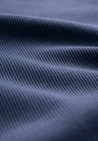 Tessuto a coste blu navy mostrato in primo piano, con una trama sottile e linee verticali pronunciate. Aspetto morbido e liscio con una leggera lucentezza.