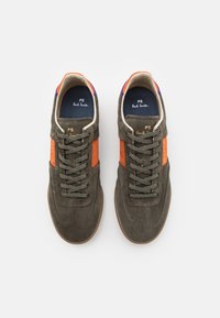 Grüne Wildledersneaker mit orangefarbenen und lila Akzenten, flachen Schnürsenkeln und einer Gummisohle. Mit Branding an der Seite und auf der Zunge.