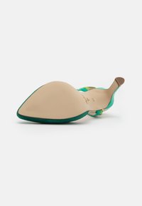 Zelená semišová bota na vysokém podpatku s špičatou špičkou, která má texturovanou béžovou podrážku a vícebarevné akcentní pásky.