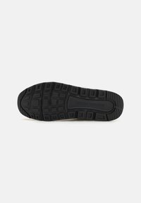 Black rubber sole with textured tread pattern, featuring rectangular and circular grooves for grip. Embossed logo detail near the heel.