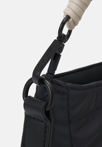 Schwarze Handtasche mit strukturiertem Oberflächenmaterial, geflochtenen Trageriemen und einem schwarzen Metallclip mit "Desigual"-Markenlogo.
