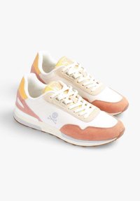 Sneakers beige e rosa con tomaia in rete e camoscio bianco, dettagli gialli e un sottile logo di teschio sul lato. Suola in gomma per la trazione.
