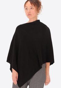 Poncho nero realizzato in un tessuto morbido e testurizzato, caratterizzato da un design ampio e drappeggiato che si restringe nella parte anteriore e copre le spalle.