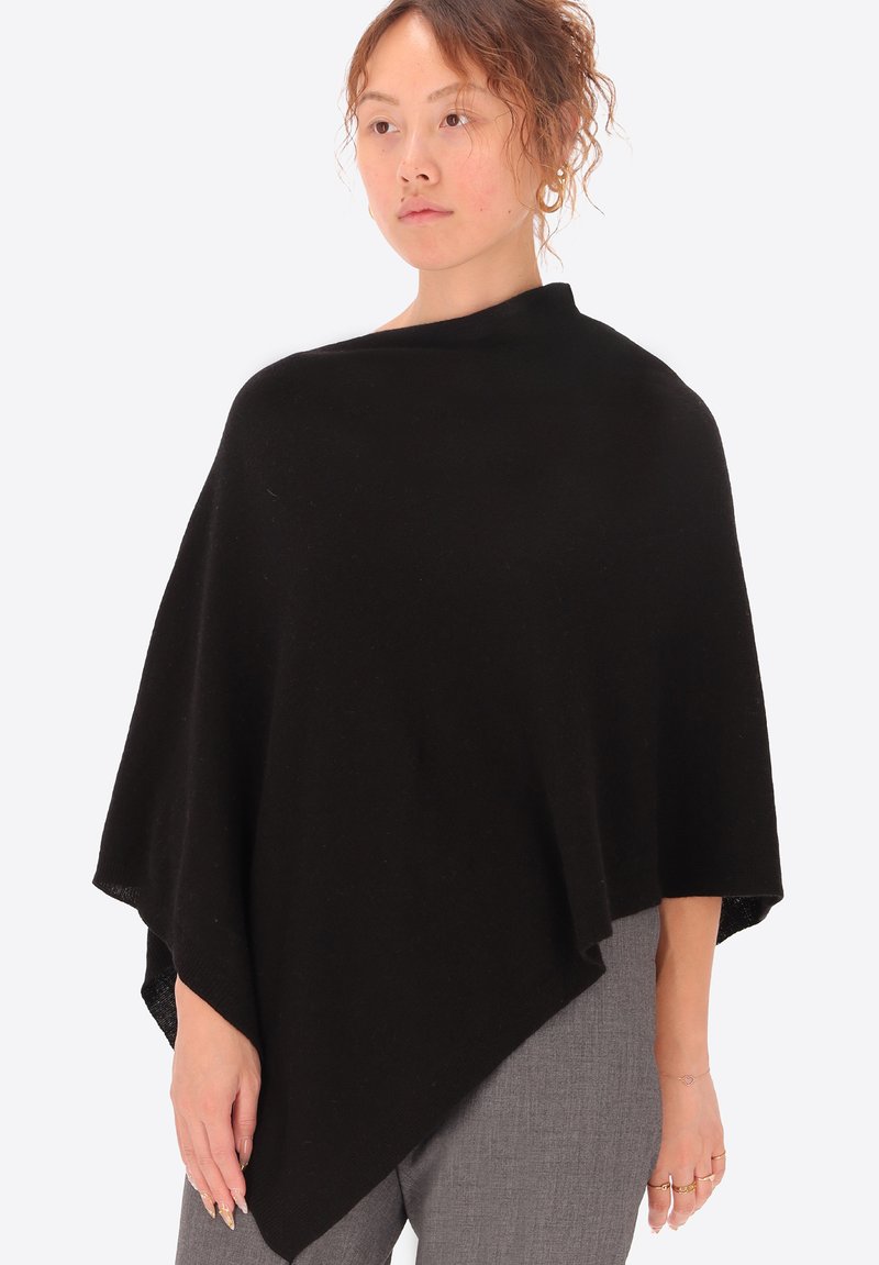 Poncho nero realizzato in un tessuto morbido e testurizzato, caratterizzato da un design ampio e drappeggiato che si restringe nella parte anteriore e copre le spalle.