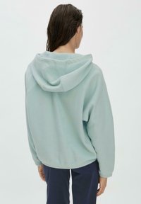 Minzgrüner Fleece-Hoodie mit weitem Schnitt, oversized Kapuze und gerippten Bündchen. Er zeichnet sich durch eine glatte Textur und ein weiches, warmes Material aus.