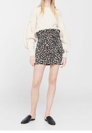 Suéter de punto crema con mangas abullonadas; falda de leopardo en blanco y negro de cintura alta; zapatos negros tipo deslizante; telas suaves y texturizadas.