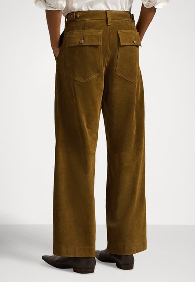 Hlače širokih nogavica od smeđeg korduroga imaju visok struk, stražnje džepove s kopčanjem na gumb i vidljive šavove.