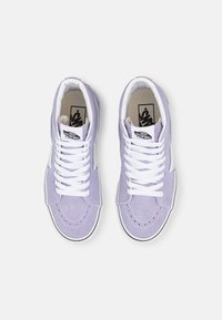 Hoge sneakers in lavendel suede met witte veters, contrasterend zwart-wit logo en klassieke rubberen zool met gestikte accenten.
