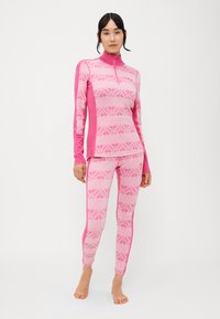 Camisola rosa de mangas longas com gola alta e leggings combinando, apresentando riscas horizontais e um padrão intrincado de renda em rosa mais claro.