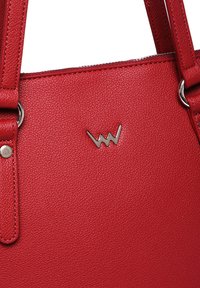 Červená kožená kabelka s texturou jemného kamene, stříbrnými kovovými doplňky a charakteristickým logem. Obsahuje robustní ramenní popruhy.