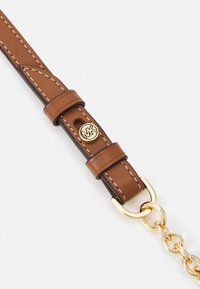 Cinturino in pelle marrone con cuciture più chiare, dotato di hardware logo in tono oro e un punto di attacco a catena. Design durevole e funzionale.