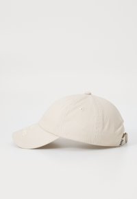 Beige cap with a curved brim, made of soft fabric. Features a stitched detail on the front and an adjustable strap at the back.