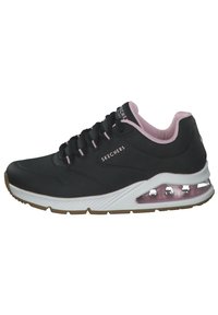 Zapatilla negra de Skechers con acentos en rosa, parte superior perforada, suela acolchada, cordones y una unidad de aire transparente en el talón. Materiales texturizados utilizados.
