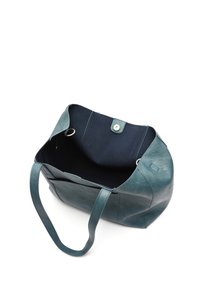 Turkusowa skórzana torebka z granatowym wnętrzem, otwarta u góry, z dwiema rączkami i zapięciem na zatrzask. Gładka tekstura z minimalnym przeszyciem i akcentami.