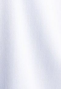 Tessuto bianco con un sottile motivo esagonale e una texture liscia, che crea un aspetto leggero e traspirante.