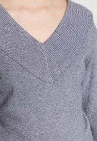 Maglione grigio a maglia con scollatura a V profonda, caratterizzato da un colletto a costine testurizzato e un tessuto morbido e liscio.