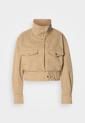 Trumpas smėlio spalvos švarkelis iš minkšto medvilnės audinio su aukštu apykakliu, sagutėmis ir dviem krūtinės kišenėmis. Pasižymi lygiu, matinio paviršiaus tekstūra.