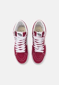 Høyhælte joggesko i burgunder semsket skinn med hvite lisser. Har polstret krage, kontrasterende sømmer og Vans-logo på tungen.