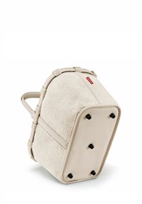 Beige Rucksack mit einer strukturierten Fleece-Oberfläche, weichem Stoff und einem stabilen Rahmen. Verfügt über einen auffälligen Griff und schwarze Füße für zusätzliche Stabilität.