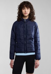 Mörkblå vadderad pufferjacka med hög krage, framdragkedja och sidofickor. Smala horisontella sektioner skapar en slank textur.