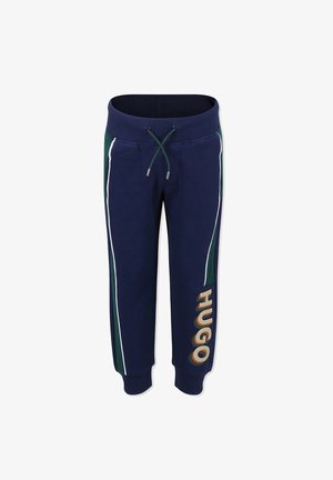 Marineblauwe sweatpants gemaakt van zacht materiaal, met witte zijstrepen en een groene accent, en een groot "HUGO"-logo op het linkerbeen.