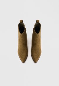 Botines de ante marrón hasta el tobillo con punteras en punta, que cuentan con patrones embosados tonal, detalles de cremallera lateral y están diseñados con tiradores para facilitar su calzado.