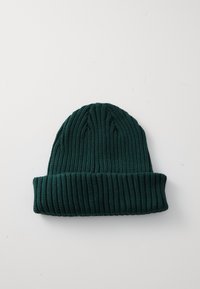 Bonnet en tricot vert foncé avec une texture côtelée et un ourlet replié. Le tissu semble doux et élastique, adapté aux temps froids.