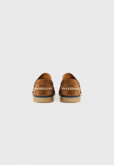 Pantofi din suede maro, cu un profil scăzut, talpă din cauciuc și cusături albe contrastante de-a lungul călcâiului. Design simplu, fără embellishments.
