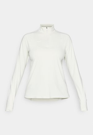 Pólvora atlética blanca de mangas largas con cuello alto y cremallera frontal de cuarto, que presenta un sutil logo en el lado izquierdo del pecho y agujeros para los pulgares en las mangas.