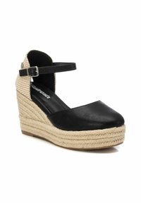 Espadrille cuña negra con parte superior sintética negra, suela intermedia de yute trenzado y tela a cuadros en la correa del tobillo. Detalle de hebilla ajustable.