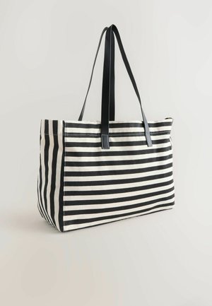 Prugasta torbica v črni in beli barvi z dvema črnima ročajema, postavljena ob svetli ozadju, ki prikazuje svojo prostorno zasnovo.