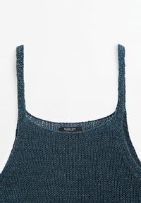 Débardeur tricoté bleu profond avec fines bretelles, présentant une texture à mailles lâches et une étiquette de marque au niveau de l'encolure.