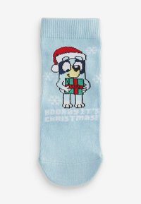 Chaussette bleue avec un oiseau de dessin animé portant un chapeau de Noël rouge, tenant un cadeau vert et rouge, avec des motifs de flocons de neige sur tout le tissu.