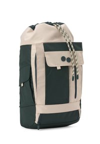 Sac à dos à cordon beige bicolore et vert foncé avec une poche à rabat sur le devant, des poches latérales et un compartiment zippé au fond.