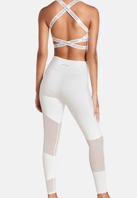 Reggiseno sportivo bianco con spalline incrociate e branding "Oceans Apart". Leggings bianchi a vita alta con pannelli in rete e design color-block.