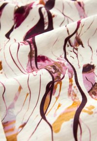 Tissu blanc avec des motifs abstraits de coups de pinceau violets, roses, orange et marron formant des lignes irrégulières et fluides.