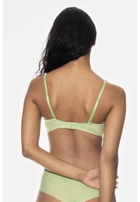 Vihreä rintaliivi, jossa on säädettävät olkaimet, sileä satiinimainen pinta ja yksinkertainen hakasuljenta takana.