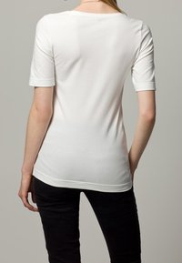 Hvid bomulds t-shirt med korte ærmer og rund halsudskæring, der går til hoften, glat tekstur, ingen synlige mønstre eller detaljer.