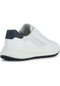 Sneaker bianca con sovrapposizioni in mesh e pelle liscia, accenti blu navy sul tallone, suola grigia testurizzata e lacci piatti. Design geometrico sottile.